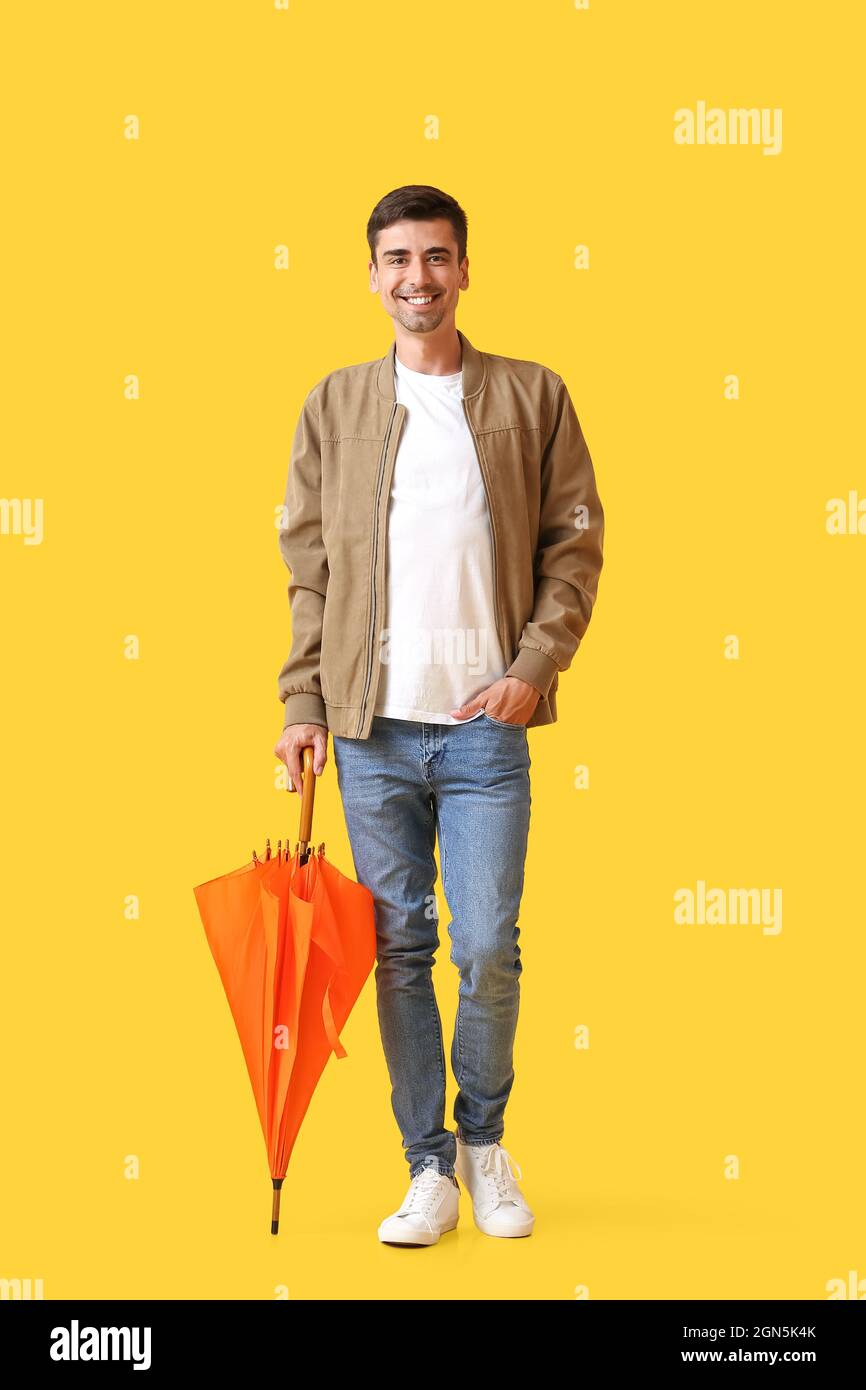 Handsome young man with umbrella on color background Stock Photo - Alamy