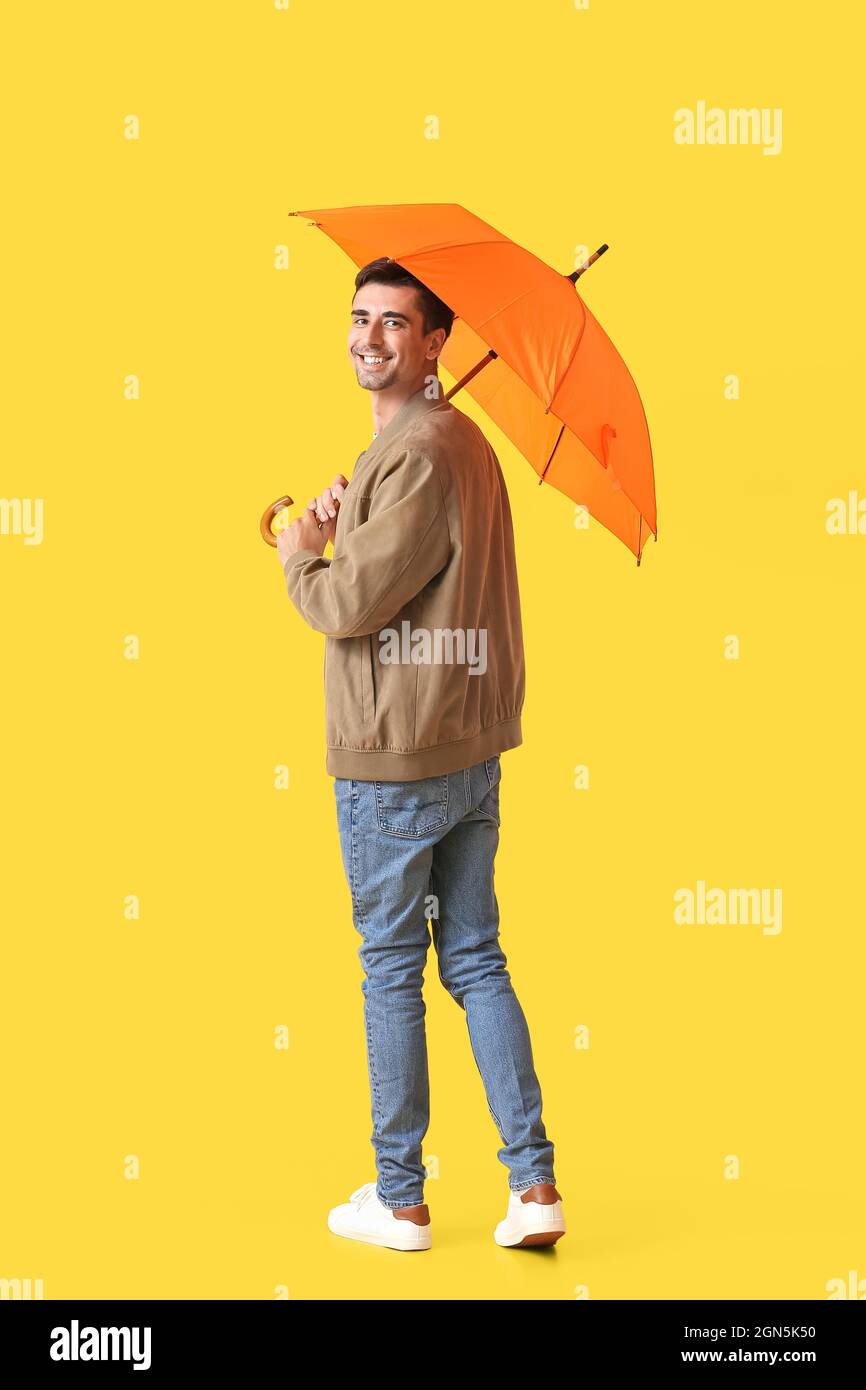 Handsome young man with umbrella on color background Stock Photo - Alamy