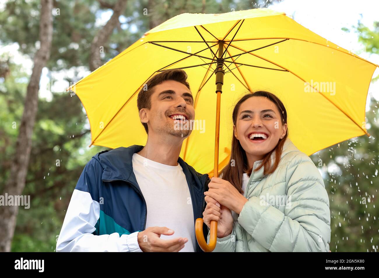 Young couple with umbrella in park Stock Photo - Alamy
