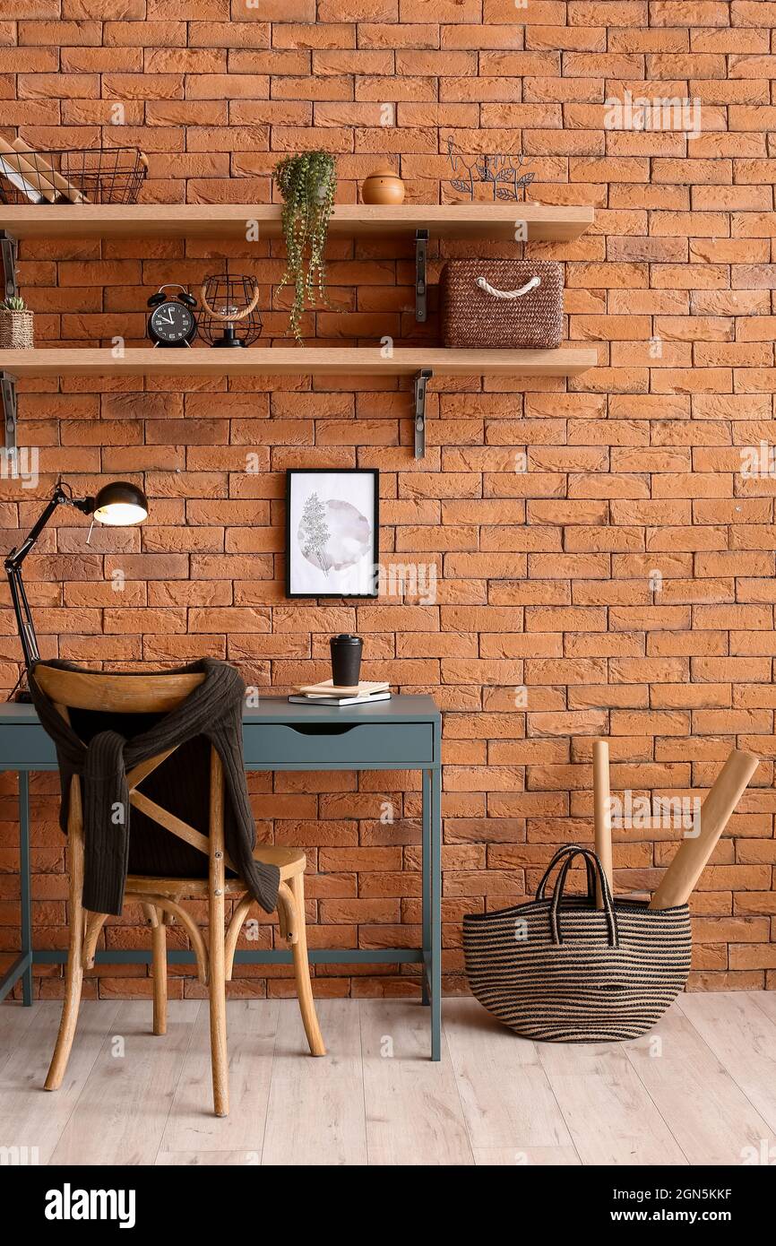 Room interior with stylish workplace and shelves on brick wall Stock