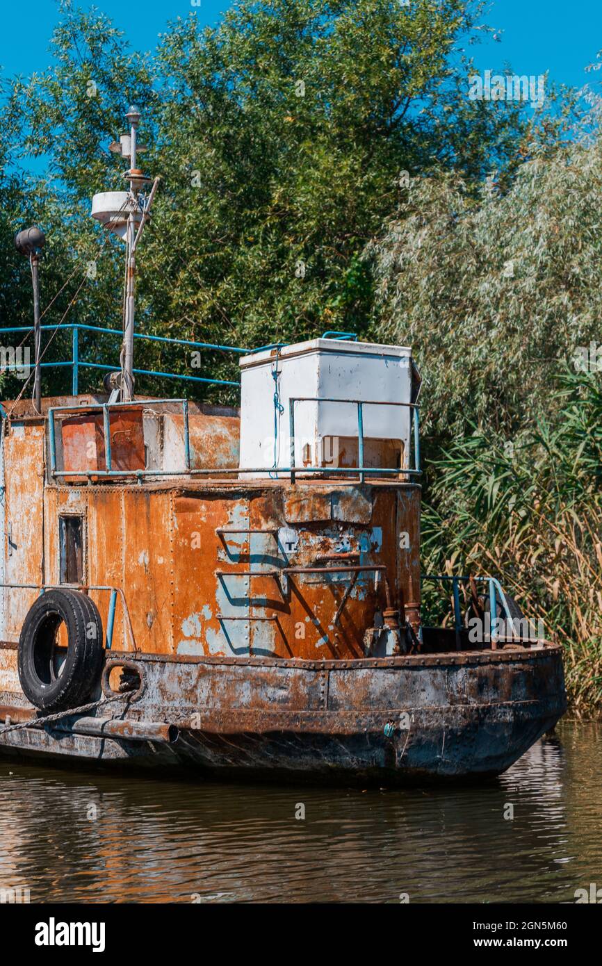Old rusty boat on the water by reeds and trees Stock Photo - Alamy