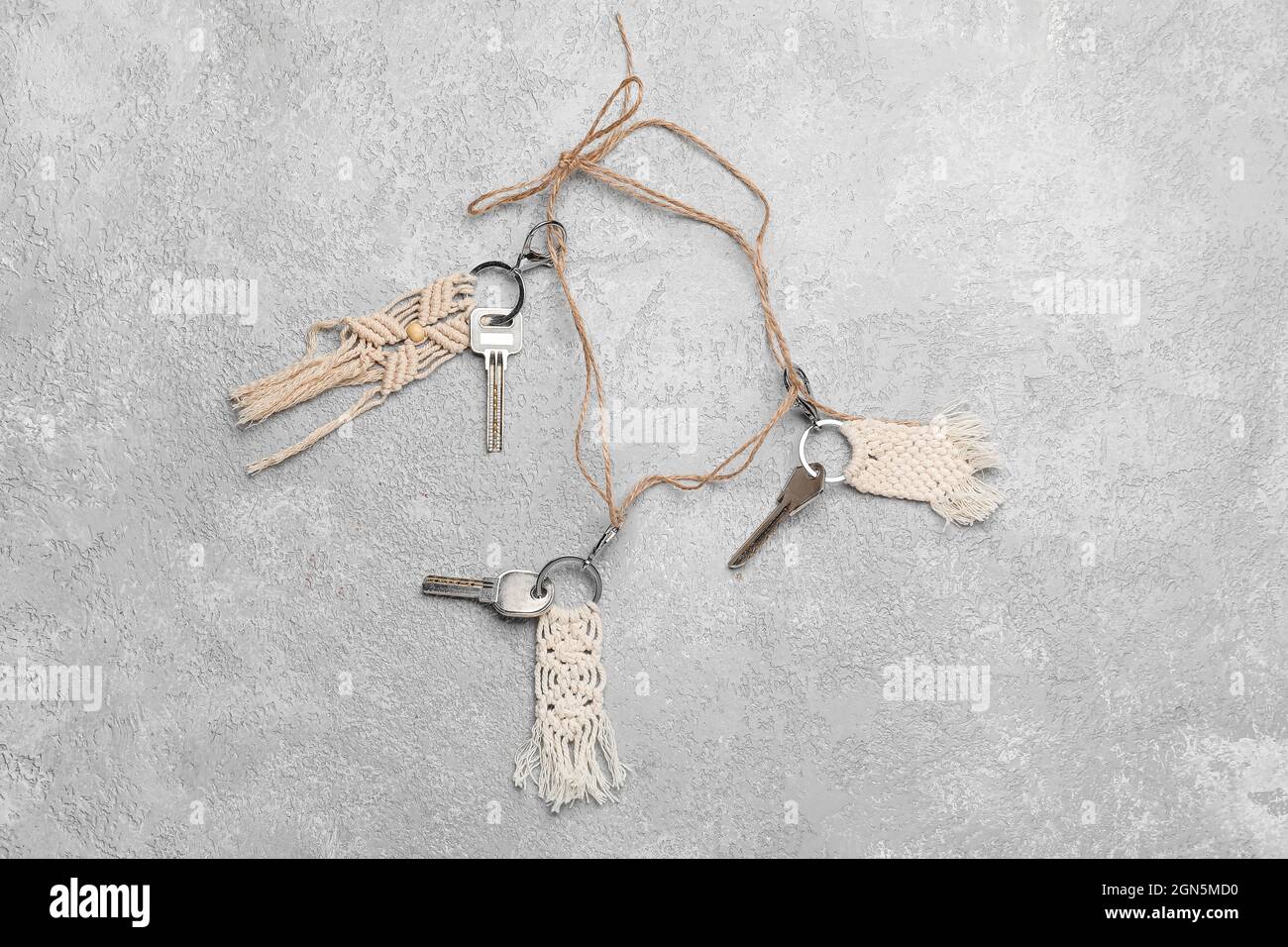 Keys with handmade cotton keychains on grey background Stock Photo