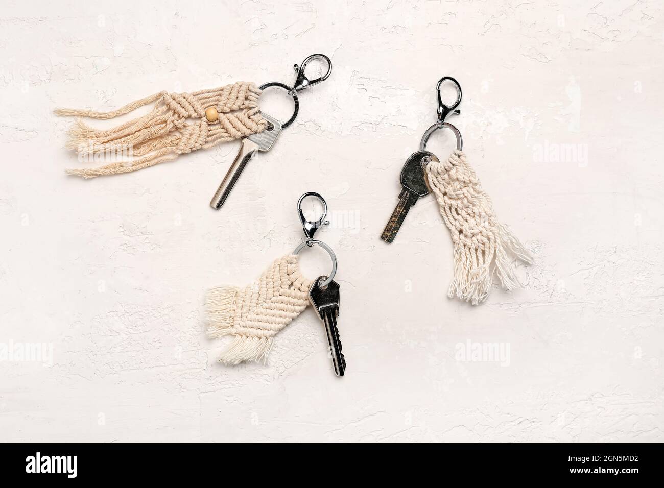 Keys with handmade cotton keychains on light background Stock Photo