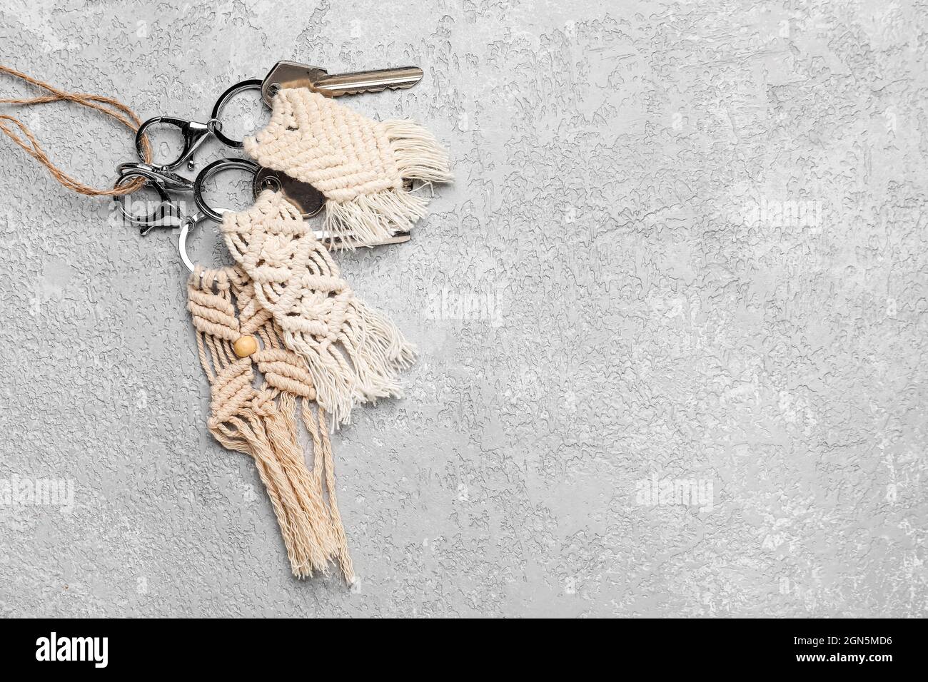 Keys with handmade cotton keychains on grey background Stock Photo
