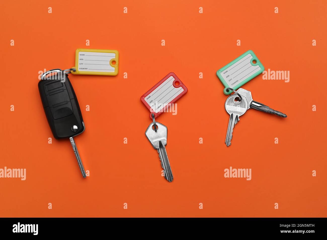 Different keys with plastic tags on orange background Stock Photo