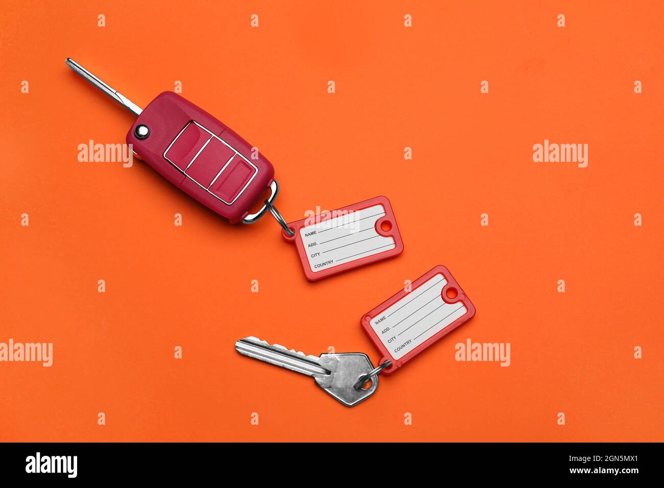 Different keys with plastic tags on orange background Stock Photo