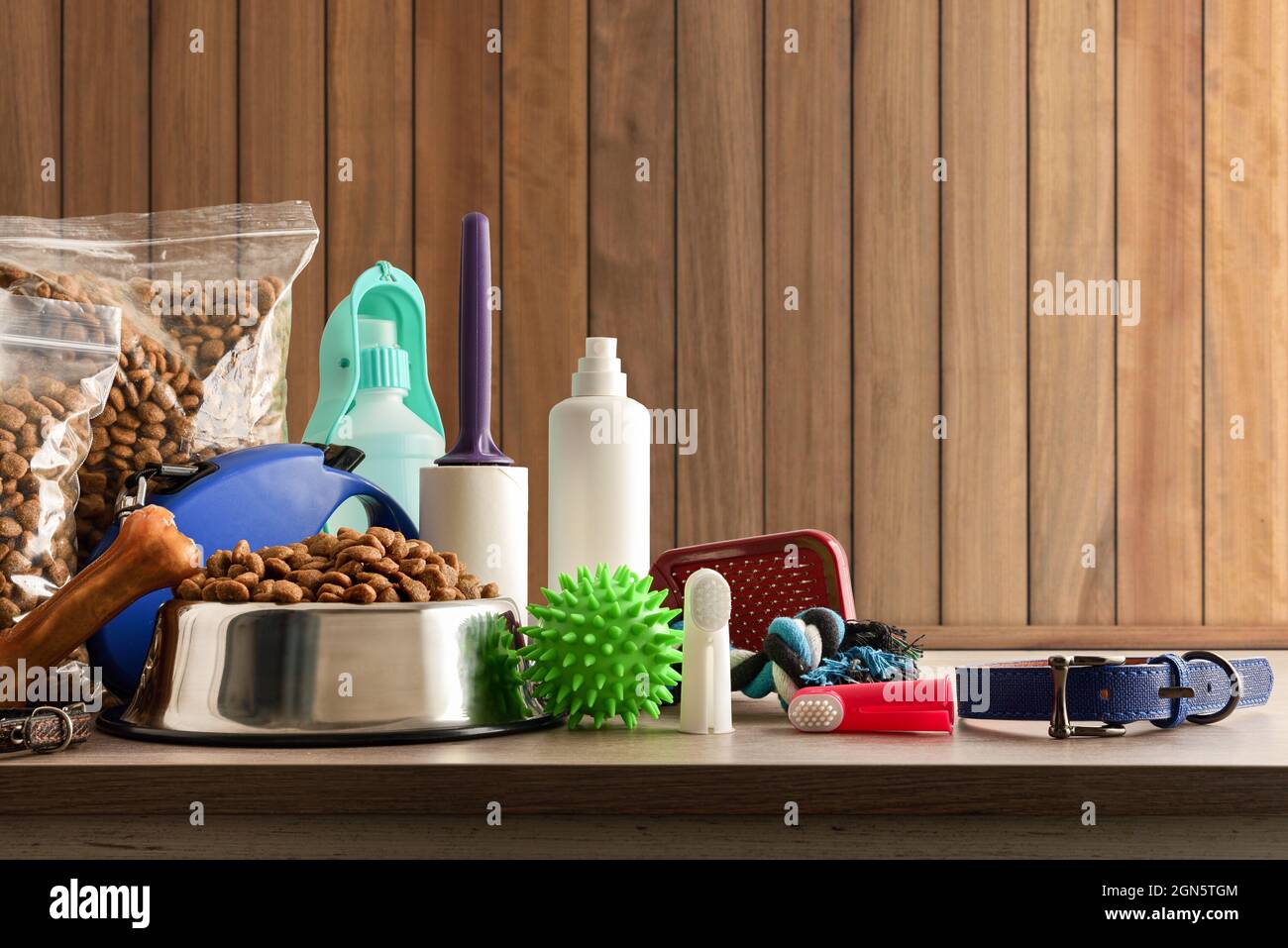 Food and accessories for walk, play and body care for the dog on wooden table. Front view. Horizontal composition. Stock Photo