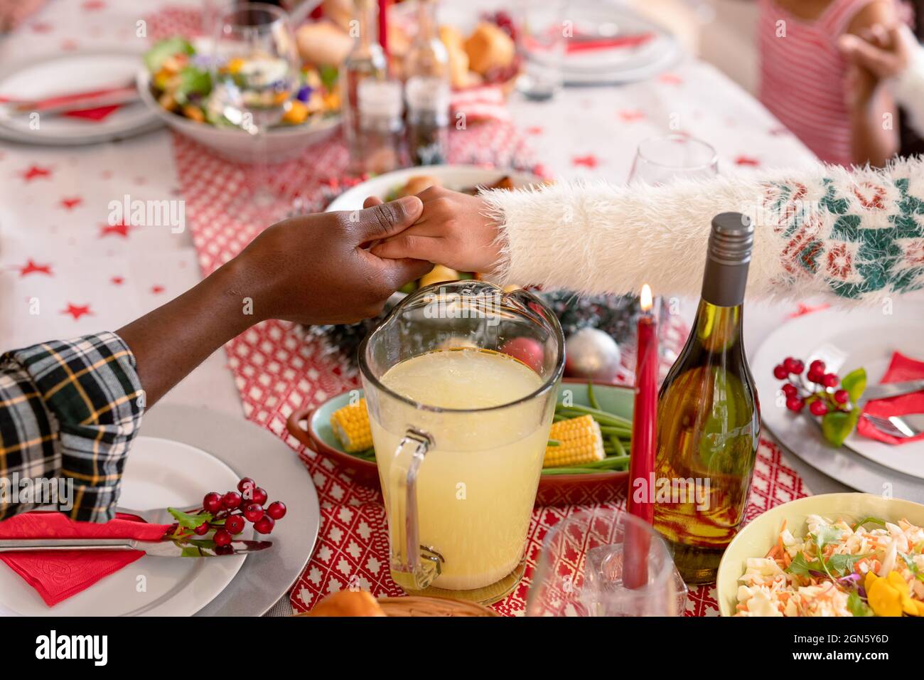 African american mother and daughter holding hands over christmas table Stock Photo
