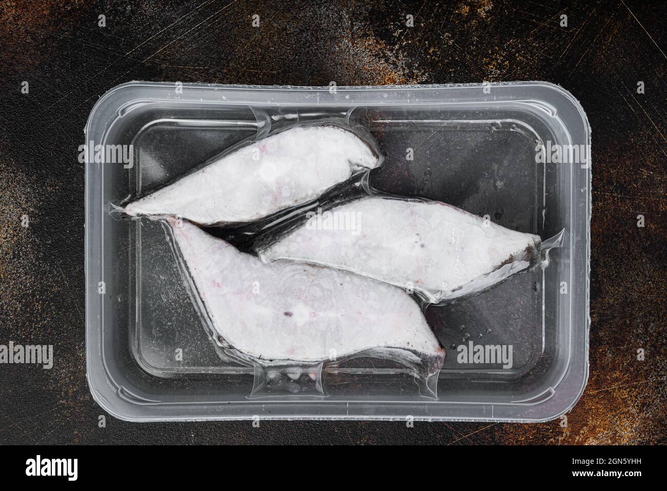 Frozen Greenland halibut steaks vacuum pack set, on old dark rustic