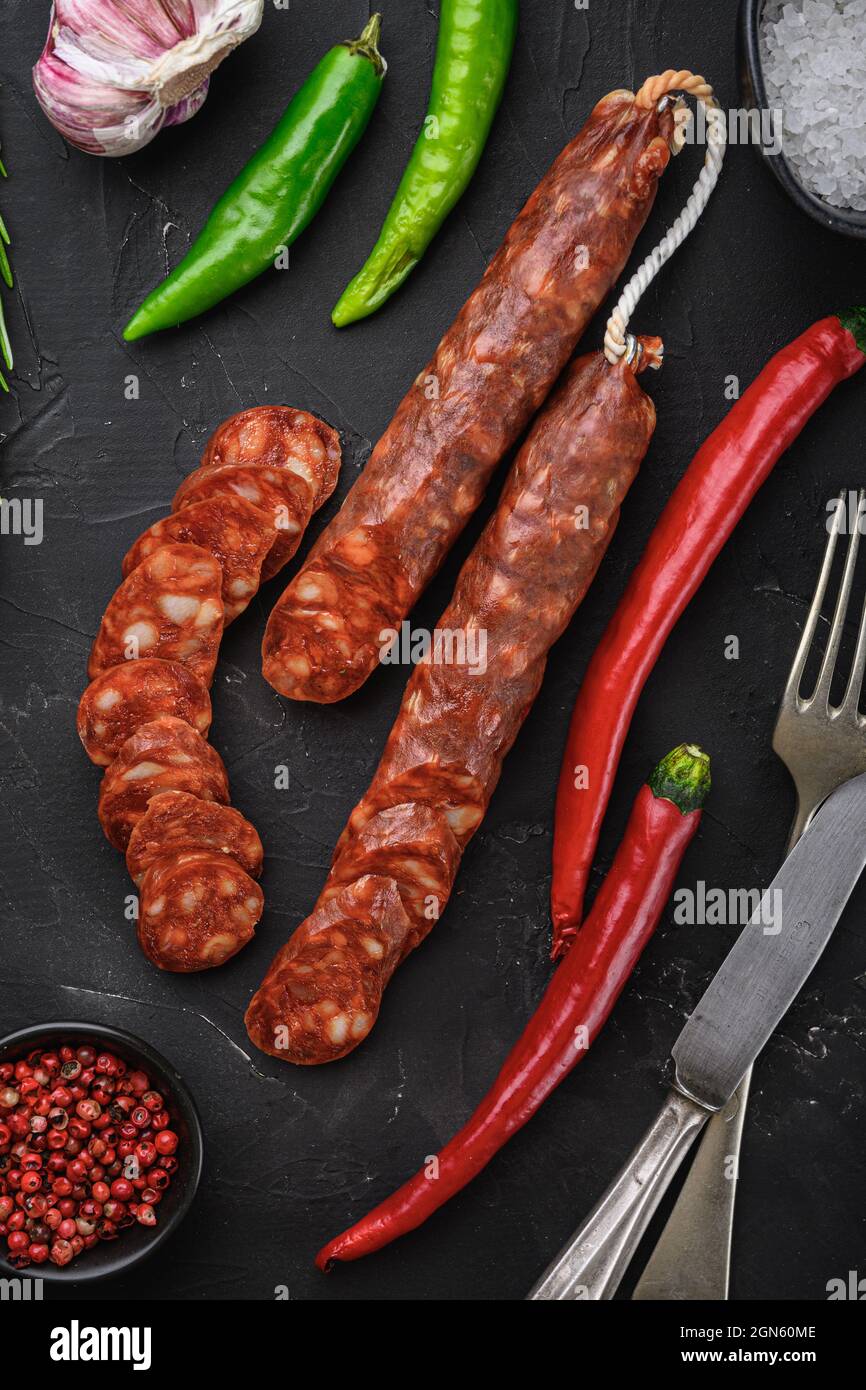 Spanish chorizo sausage slices with herbs and spices on black textured ...
