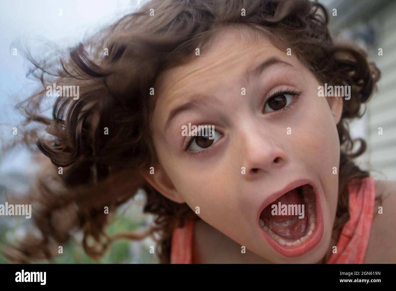 close up portrait of young girl having fun open mouth making silly faces at camera on a sunny summer day Stock Photo