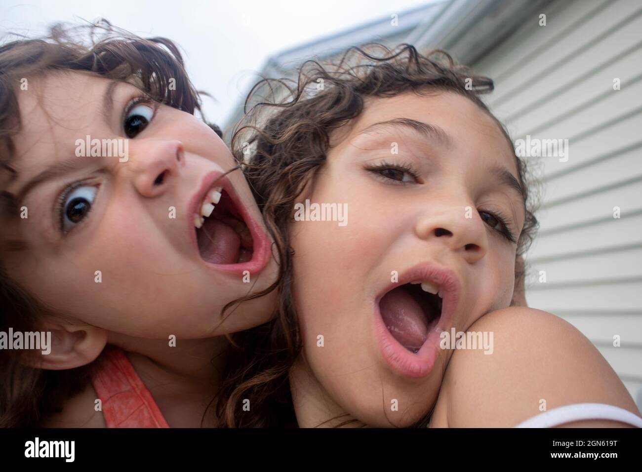 close up portrait of young girls having fun open mouth making silly faces at camera on a sunny summer day Stock Photo