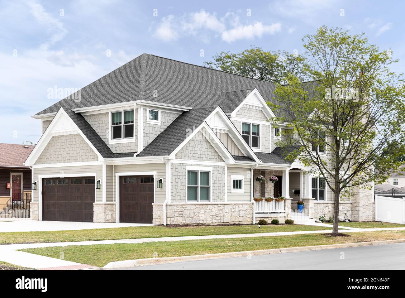 A new, white and tan modern farmhouse with dark brown garage doors and