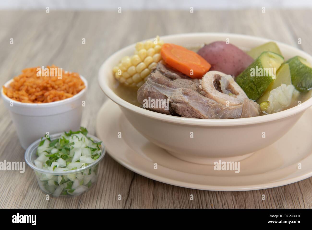Hearty bowl of Caldo de res Mexican beef stew hot from the stove and served with rice and pico