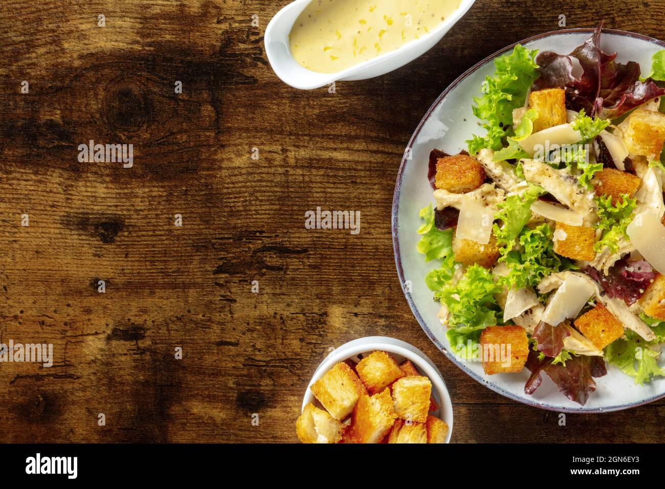 Chicken Caesar salad, overhead flat lay shot with the classic mayonnaise based sauce and croutons, on a dark rustic wooden background Stock Photo