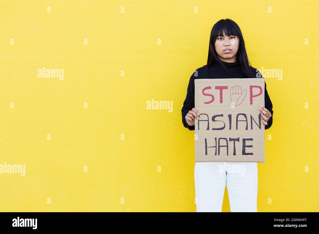 Vietnamese young woman protesting for equal rights while standing against wall Stock Photo