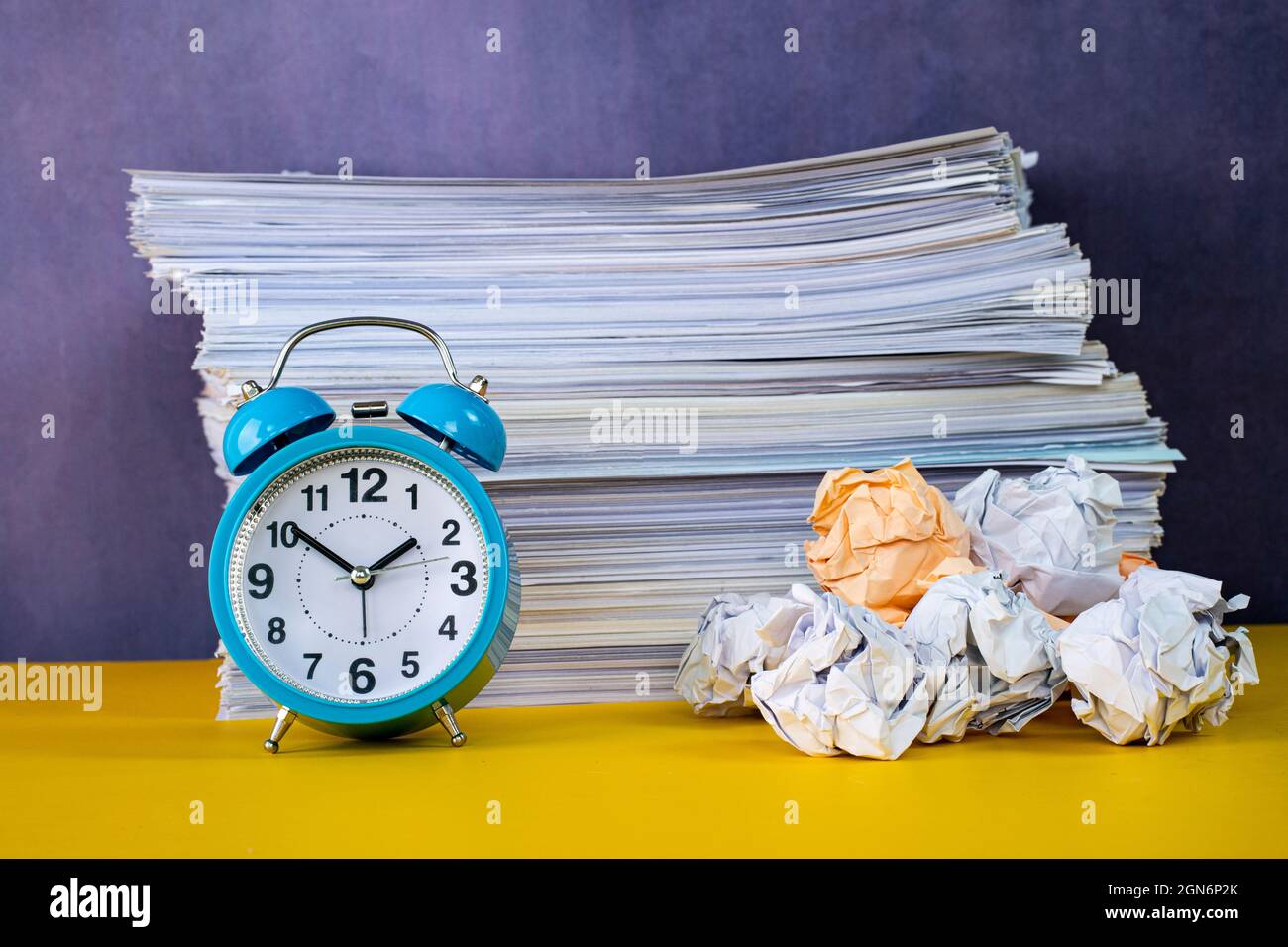 Business concept. Layout of alarm clock, stack of papers and crumpled papers depicting procrastinate Stock Photo