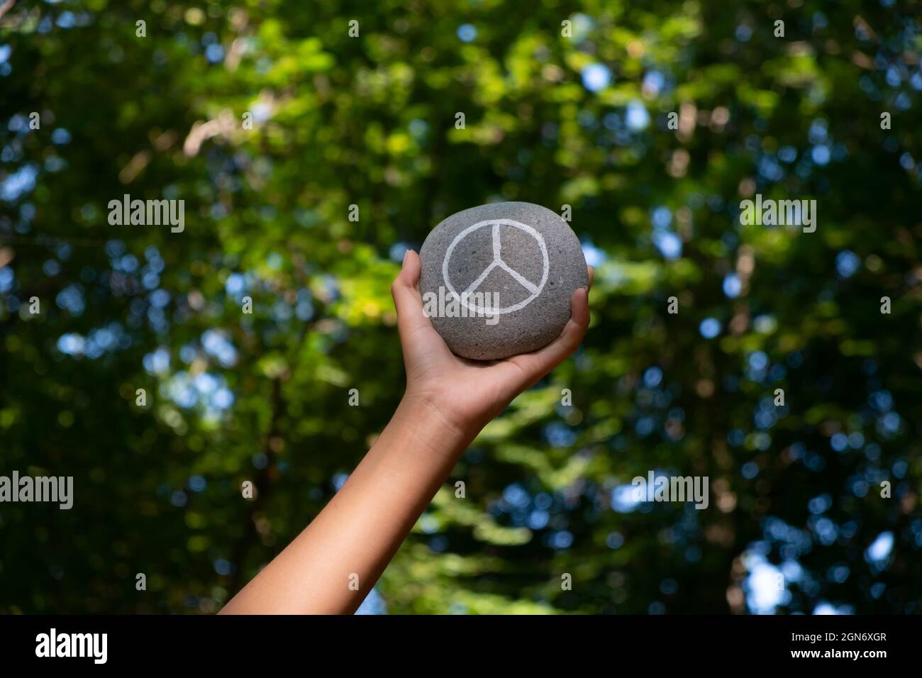 Peace symbol in hands of a child surronded by nature Stock Photo