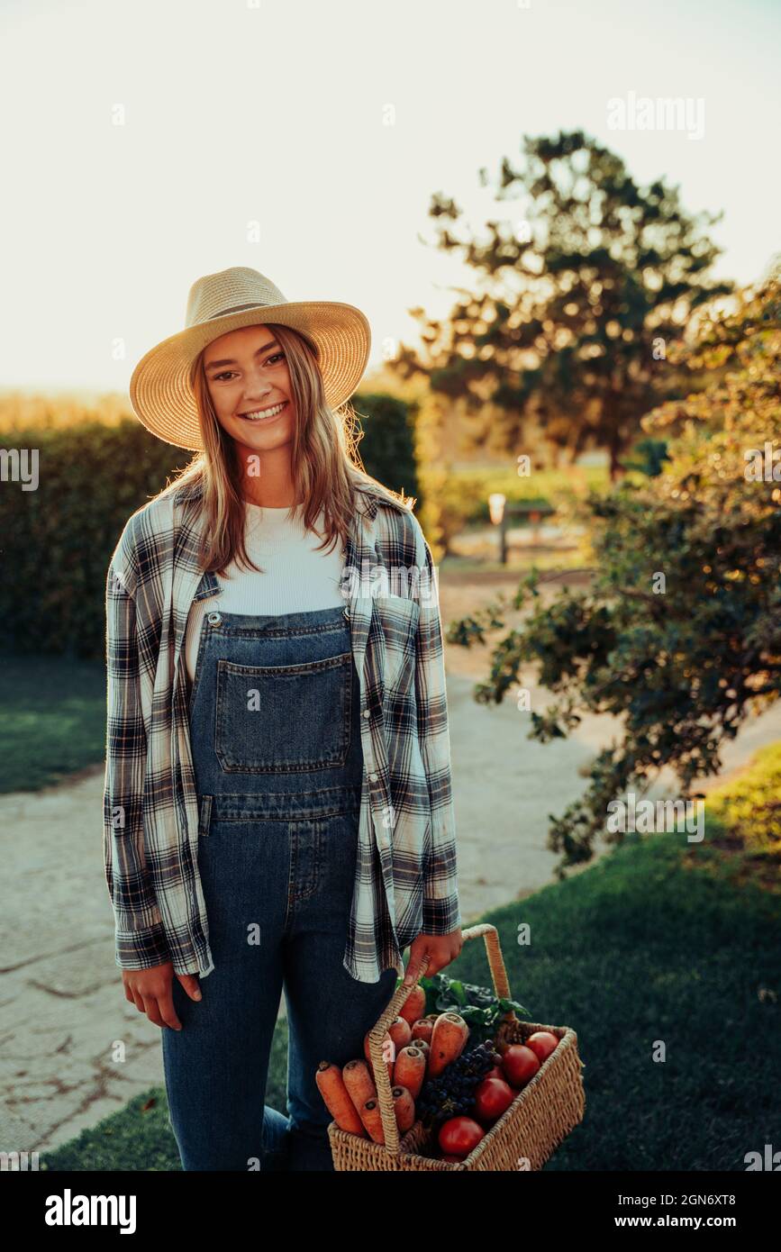 Caucasian female farmer smiling after successfully picking fresh vegetables from garden  Stock Photo