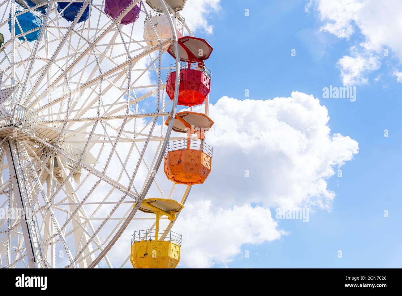 Colorful ferris wheel on a shiny day with some clouds in the background ...