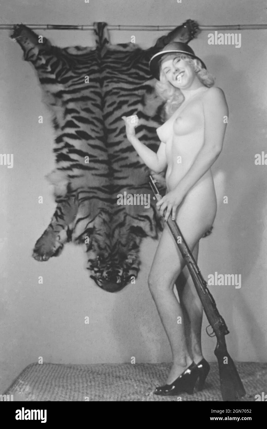 1940s / 1950s nude glamour model with gun and tiger skin Stock Photo