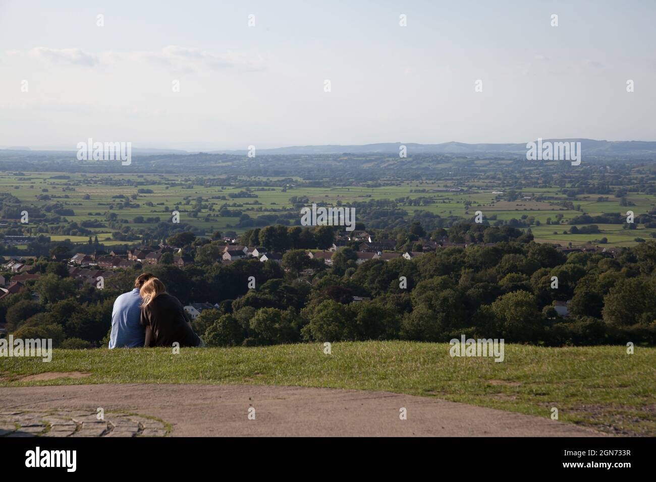 A couple cuddle on Glastonbury Tor, with views across Somerset in the UK Stock Photo