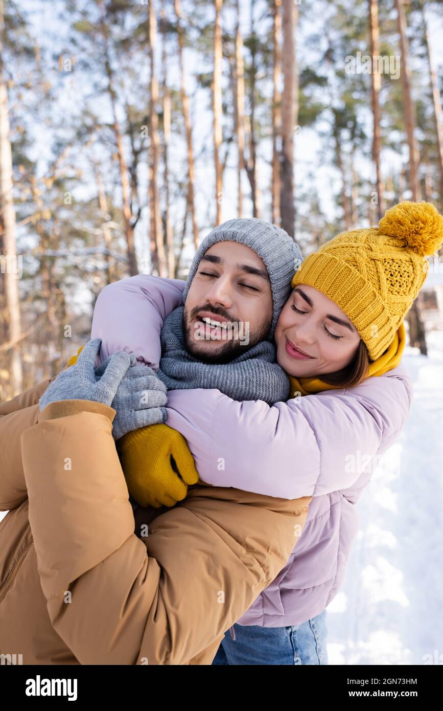 Young woman hugging boyfriend with closed eyes in winter park Stock ...