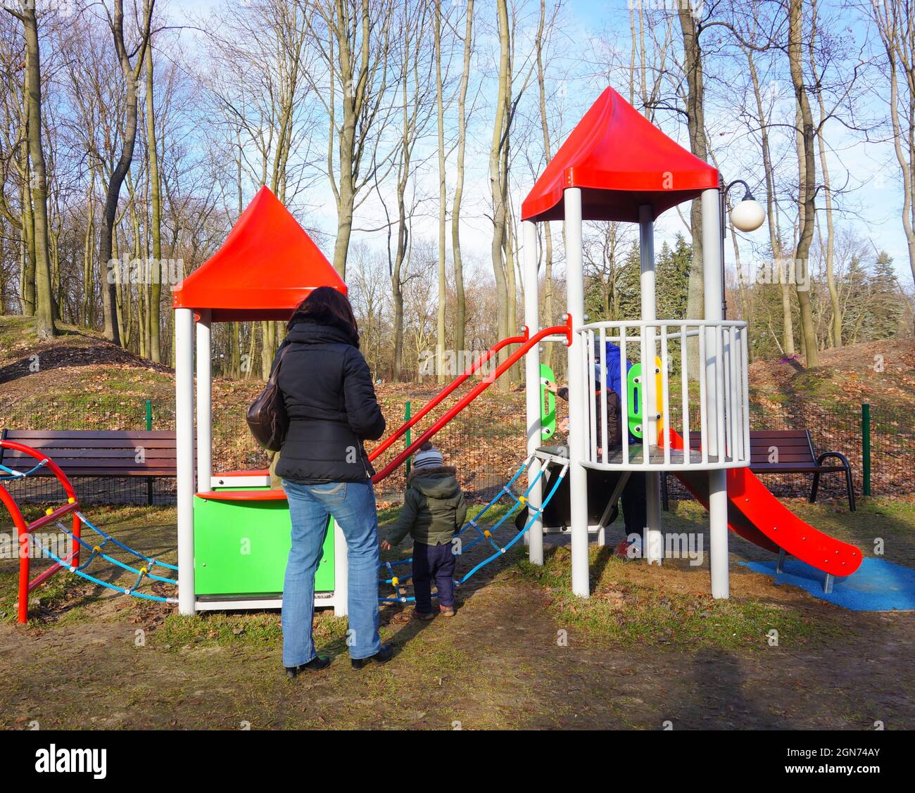 POZNAN, POLAND - Feb 07, 2016: An unidentified woman standing with child by a climb equipment on a play ground at the Citadel park Stock Photo