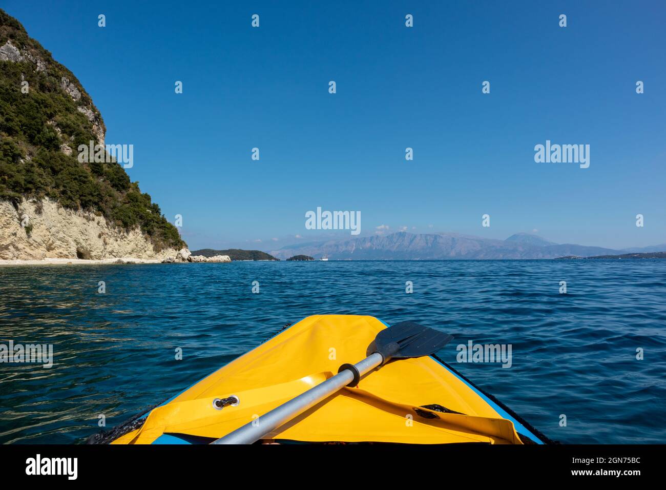 Yellow raft boat and paddle on blue clear calm Ionian Sea bay, view from boat. Nice clouds reflection and scenic rocky cliffs coast. Lefkada island in Stock Photo
