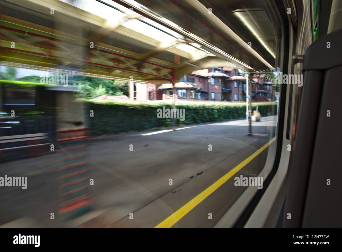 View of train station platform from within train, with some motion blur as the train departs. Stock Photo