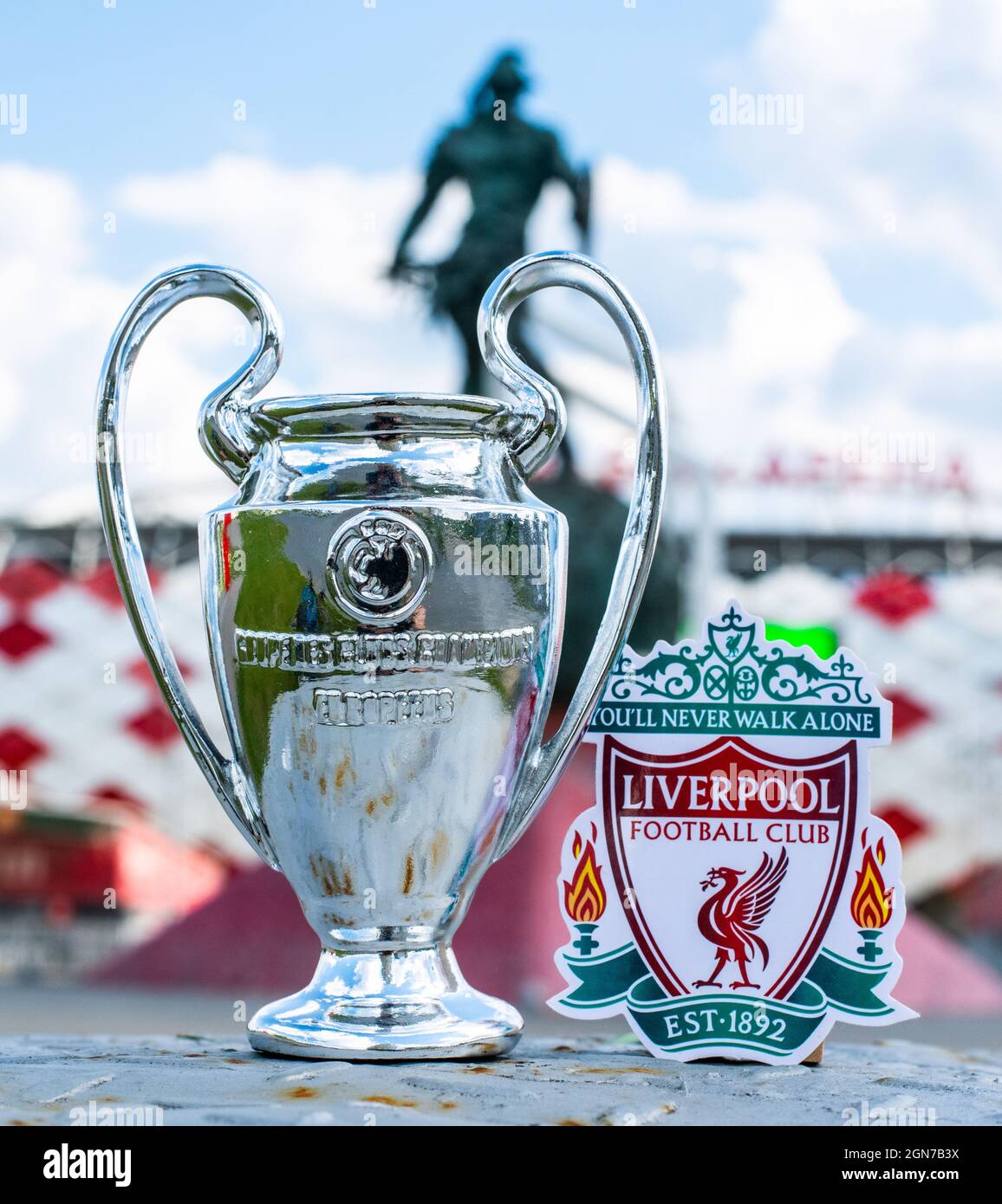 June 14, 2021 Liverpool, UK. Liverpool F.C. Football Club emblem and the UEFA Champions League Cup against the backdrop of a modern stadium. Stock Photo