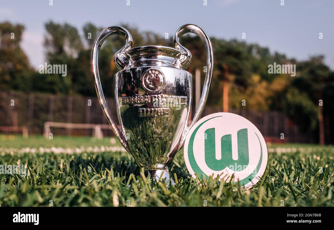 August 30, 2021 Wolfsburg, Germany. The emblem of the football club VfL Wolfsburg and the UEFA Champions League Cup on a green lawn. Stock Photo