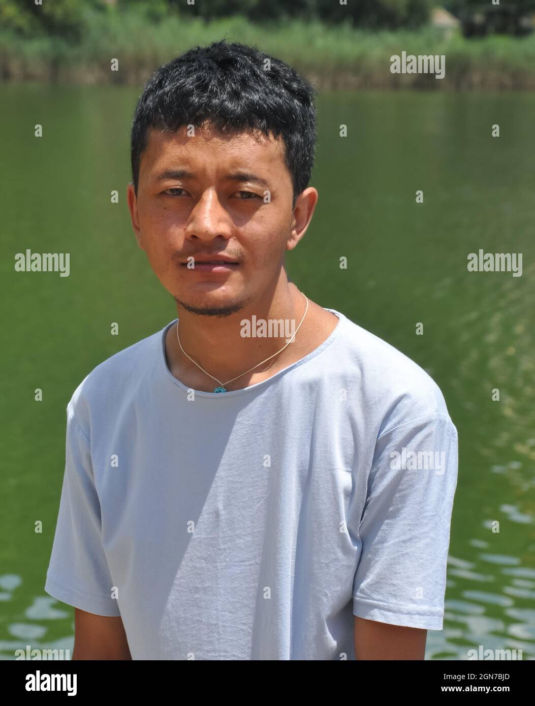Portrait of a Ladakhi (North Indian) young guy looking at camera and standing beside of lake Stock Photo
