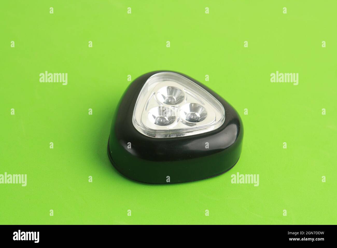 Triangular black flashlight on a green surface Stock Photo - Alamy
