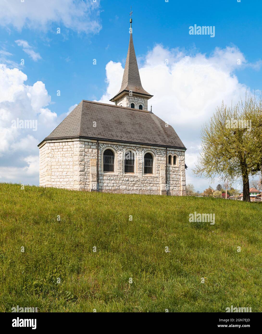 Characteristic church in the green field in the Swiss Alps of the Canton Jura. Nobody inside. Cloudy day. Stock Photo