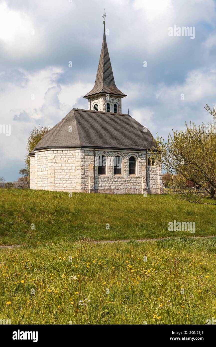 Characteristic church in the green field in the Swiss Alps of the Canton Jura. Nobody inside. Cloudy day. Stock Photo