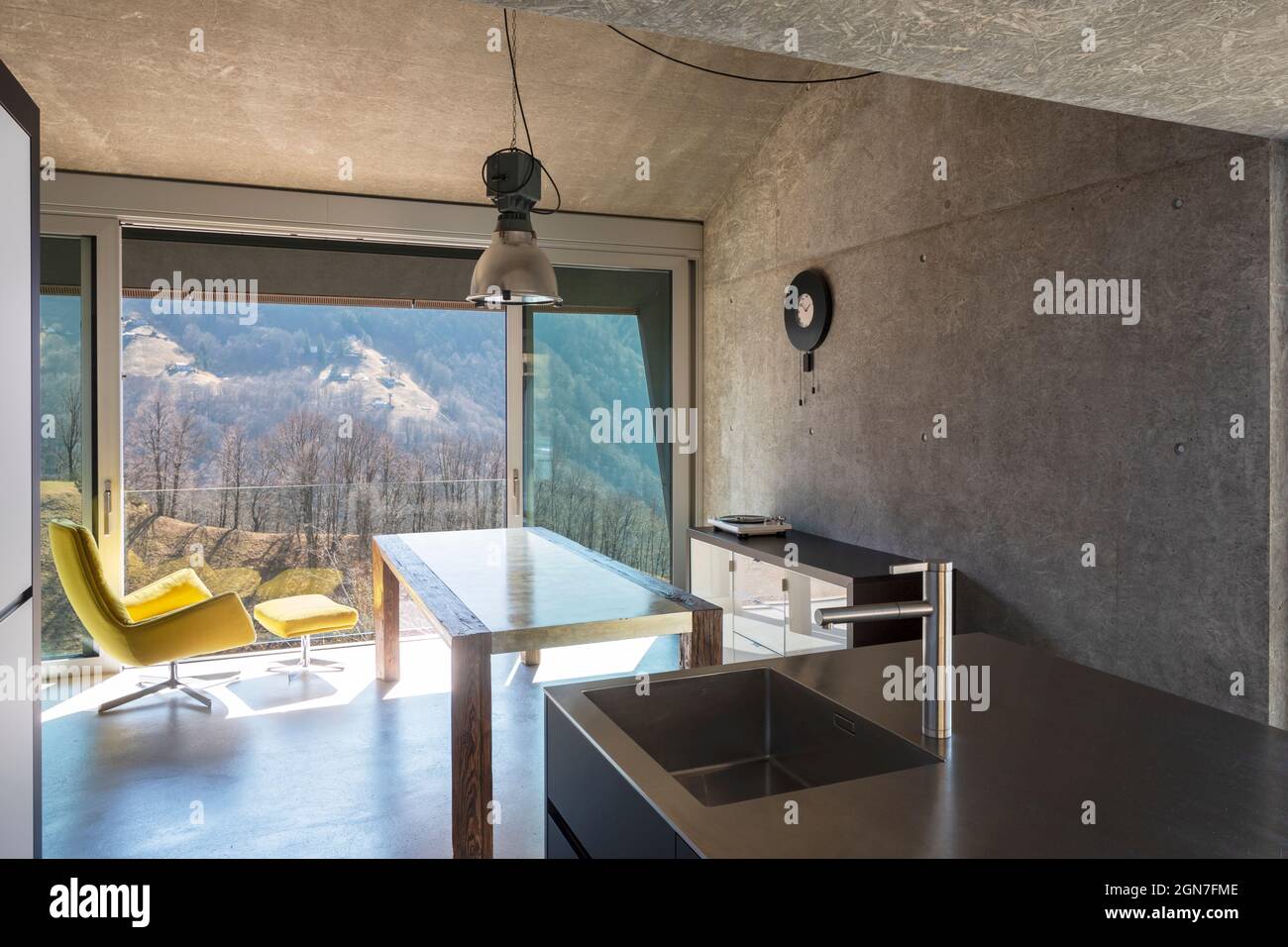 Detail of modern kitchen island, sink. Interior of a beautiful modern house, with a table, a yellow armchair and a view of nature. Nobody inside Stock Photo