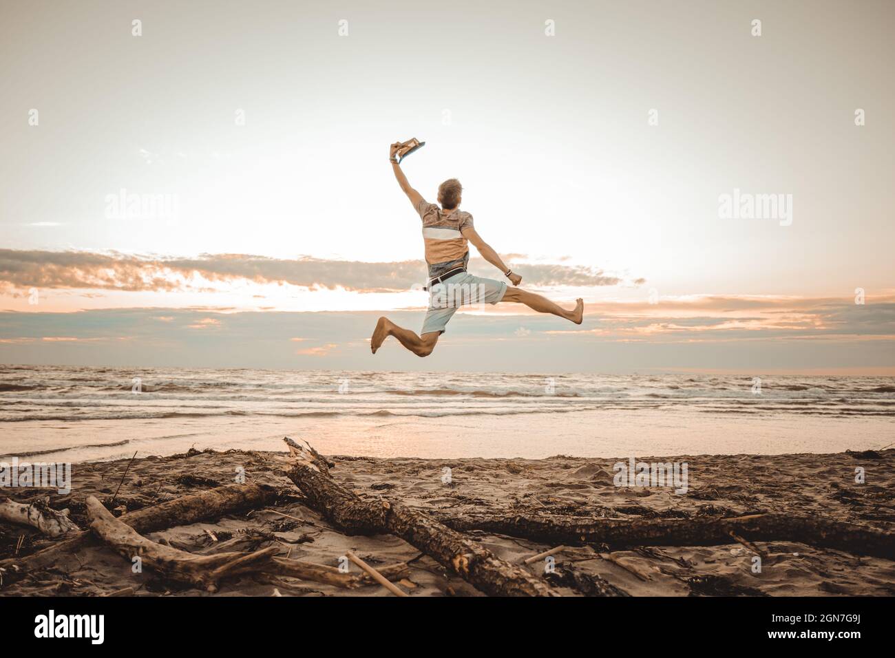 Happy boy enjoying summer holidays on beach at sunset - Young man jumping on the beach at the sunrise - Vacations concept6 Stock Photo