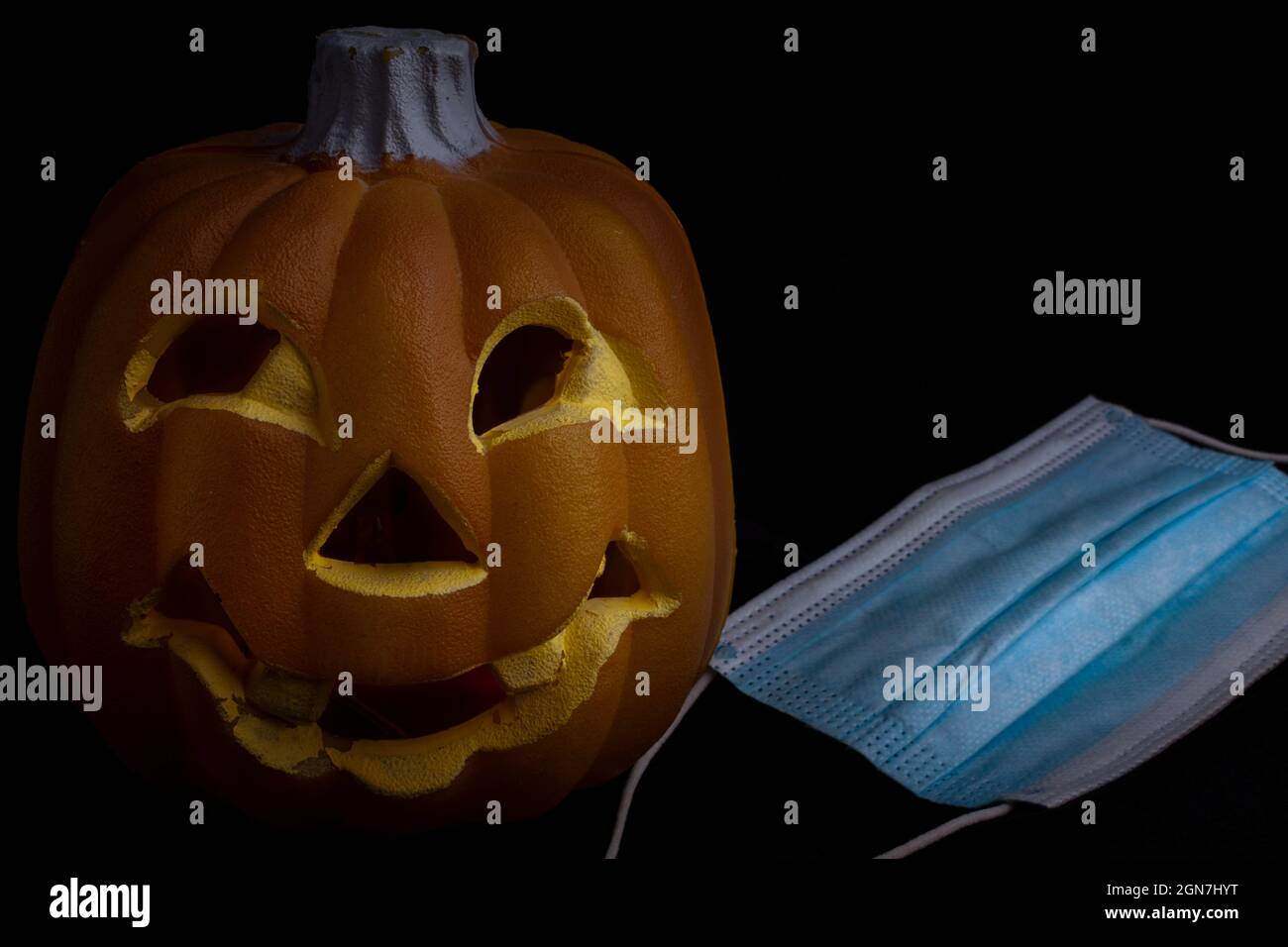 halloween in the age of coronavirus - pumpkin and face mask on black background Stock Photo