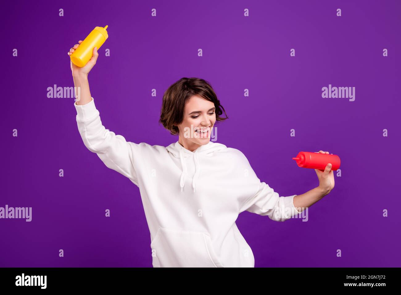 Photo portrait girl keeping mustard ketchup dancing happy isolated
