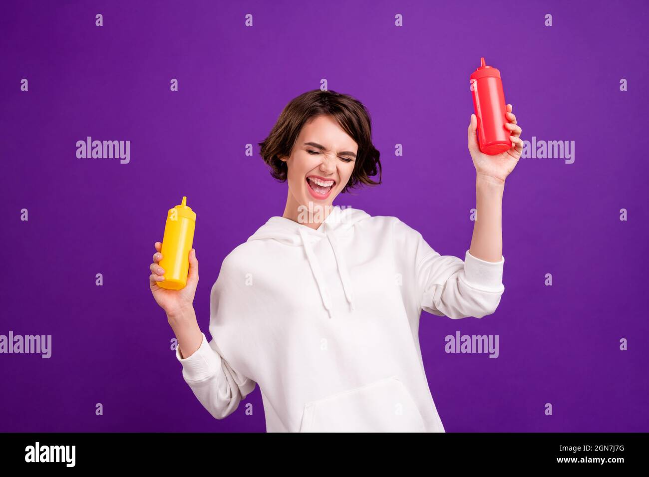 Photo portrait girl laughing keeping mustard ketchup bottles isolated