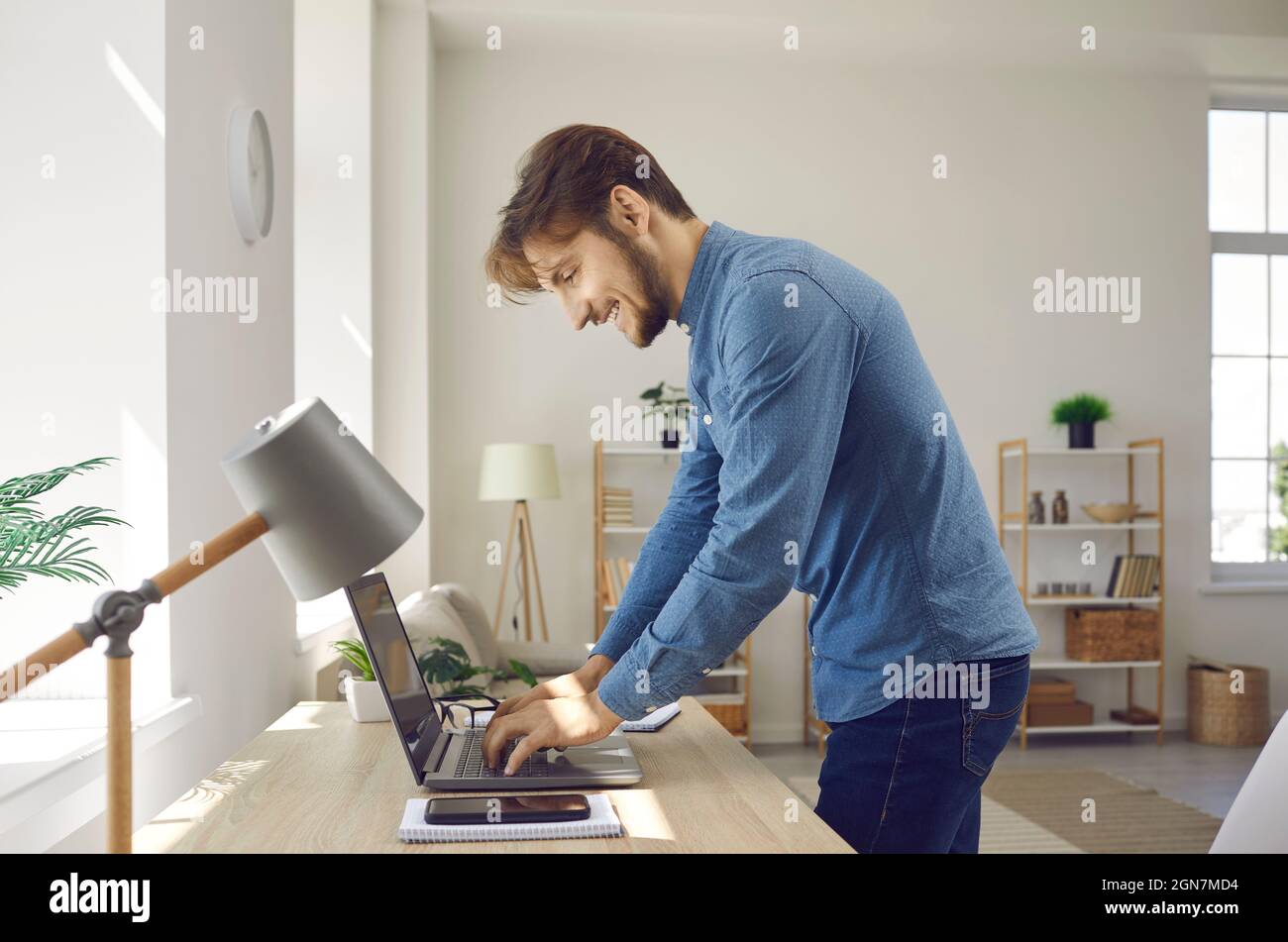 Happy young businessman or freelancer writing text on notebook while working at home office. Stock Photo