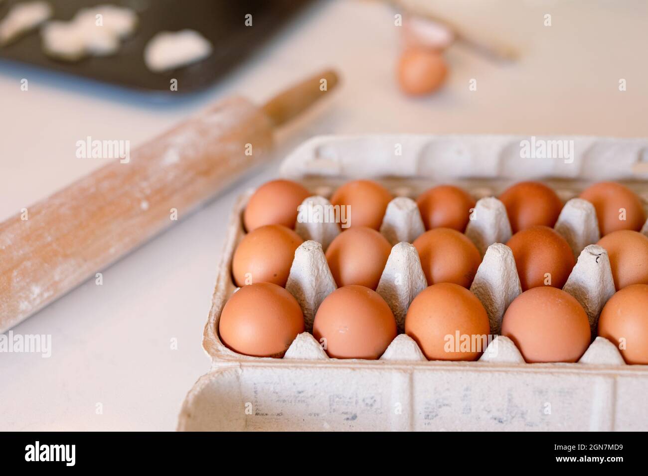 Box full of eggs and rolling pin lying on table in kitchen Stock Photo