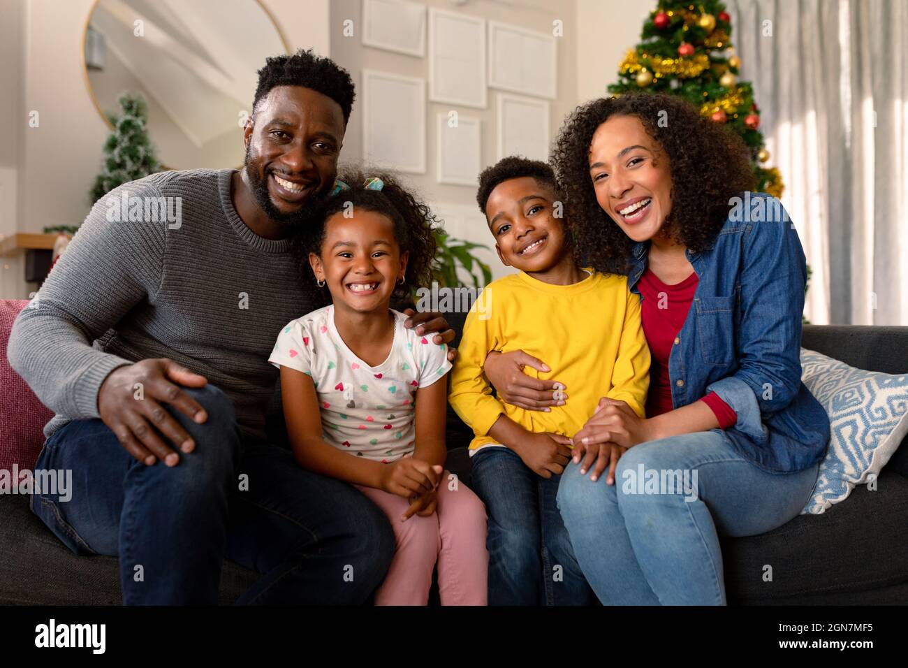 Happy african american family sitting on sofa and looking at camera ...