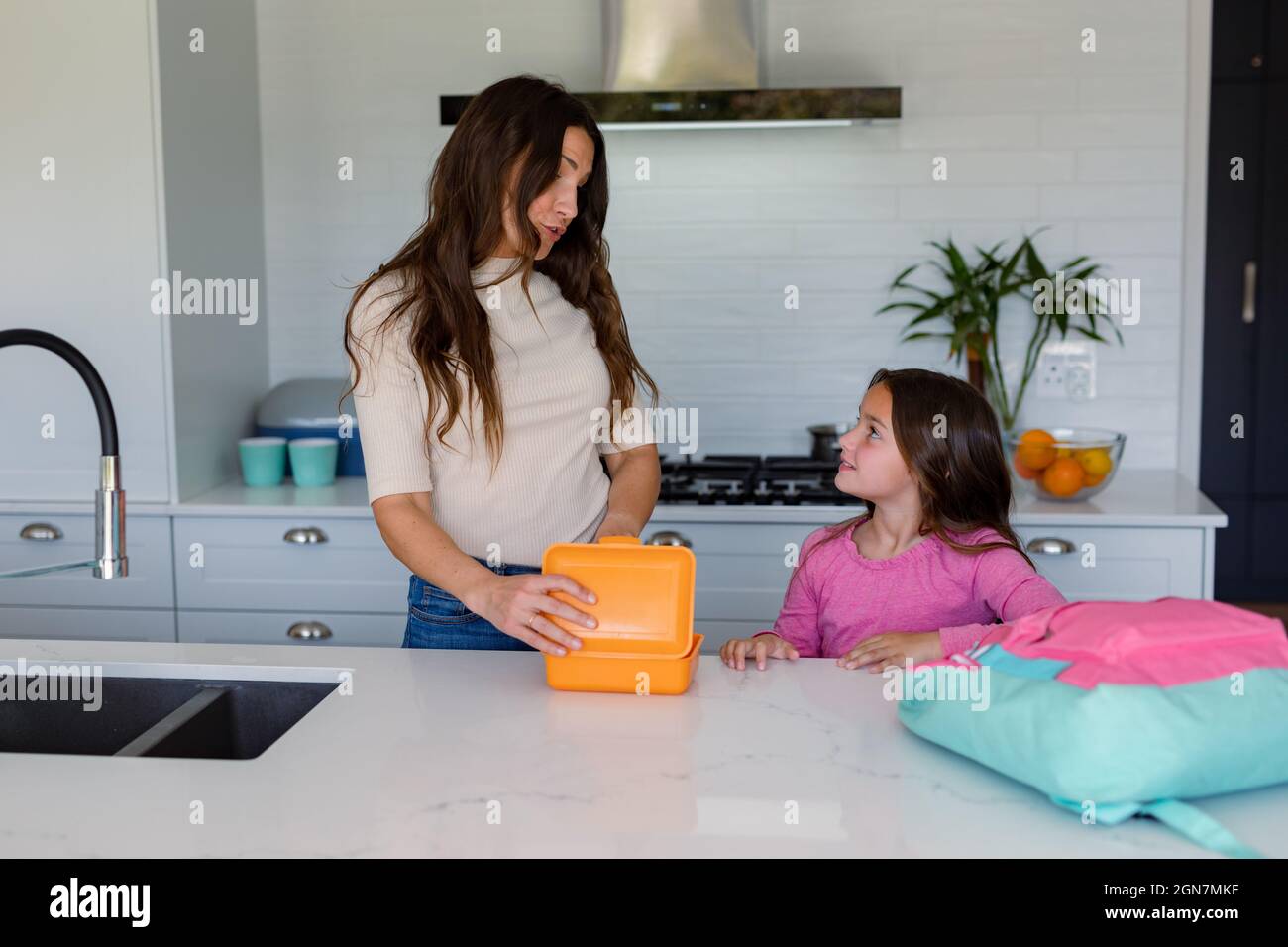 Happy caucasian mother and daughter preparing lunchbox to school in kitchen Stock Photo