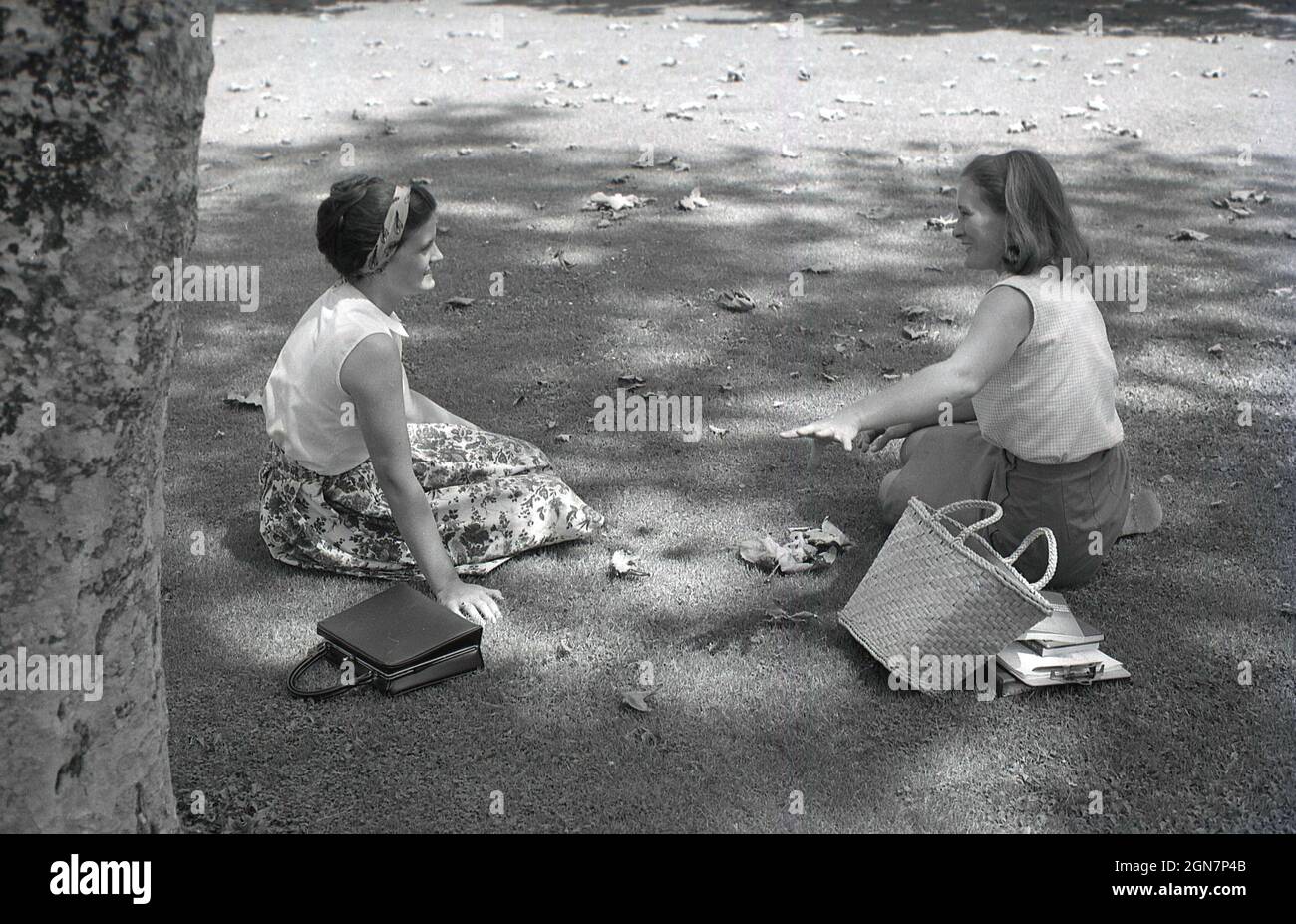 1964, historical, two young female college students, new undergraduates, sitting on the grass at tbe campus, California, USA. Stock Photo