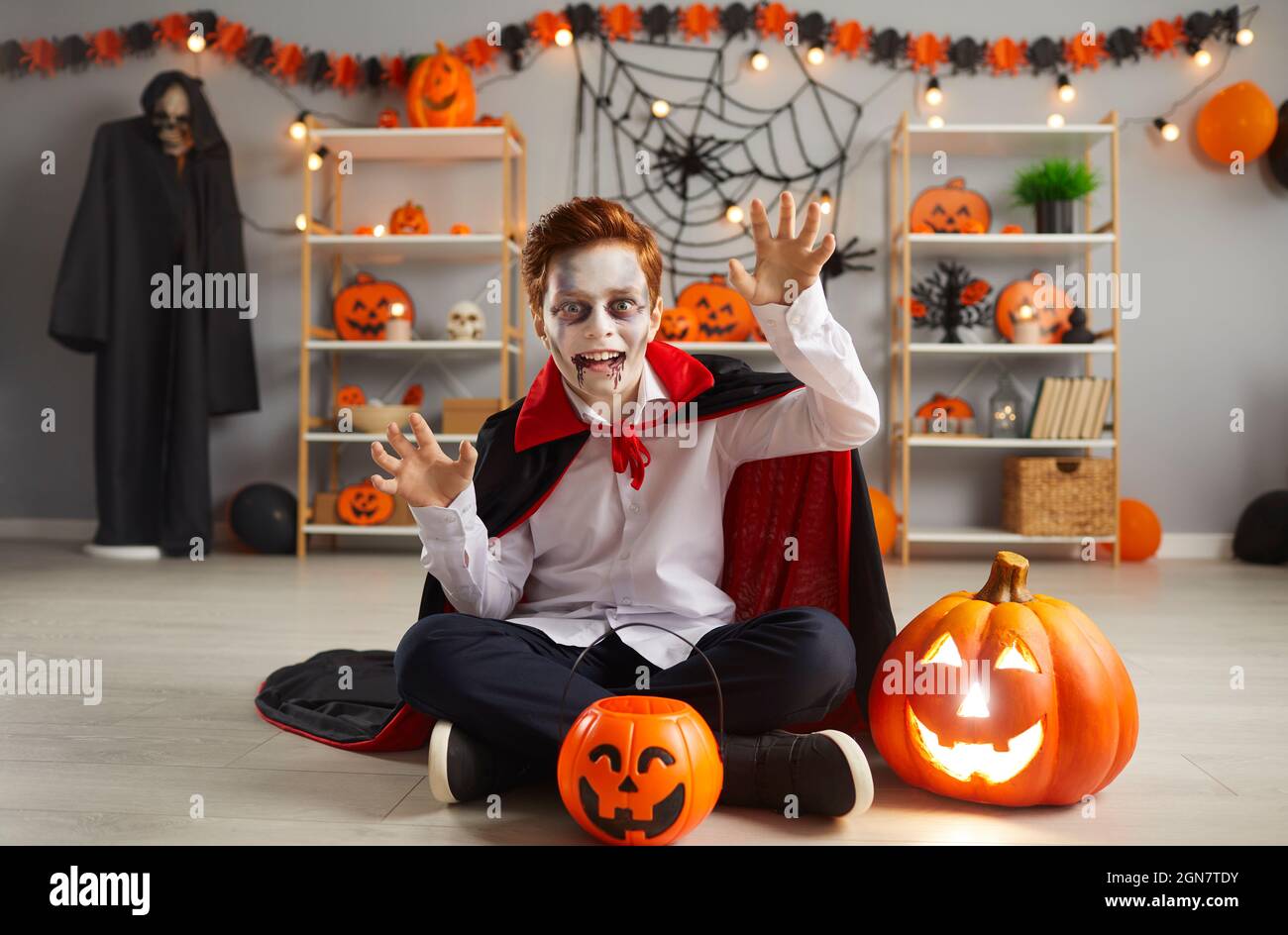 Portrait of boy dressed up as scary vampire for Halloween night sitting on floor at home Stock Photo