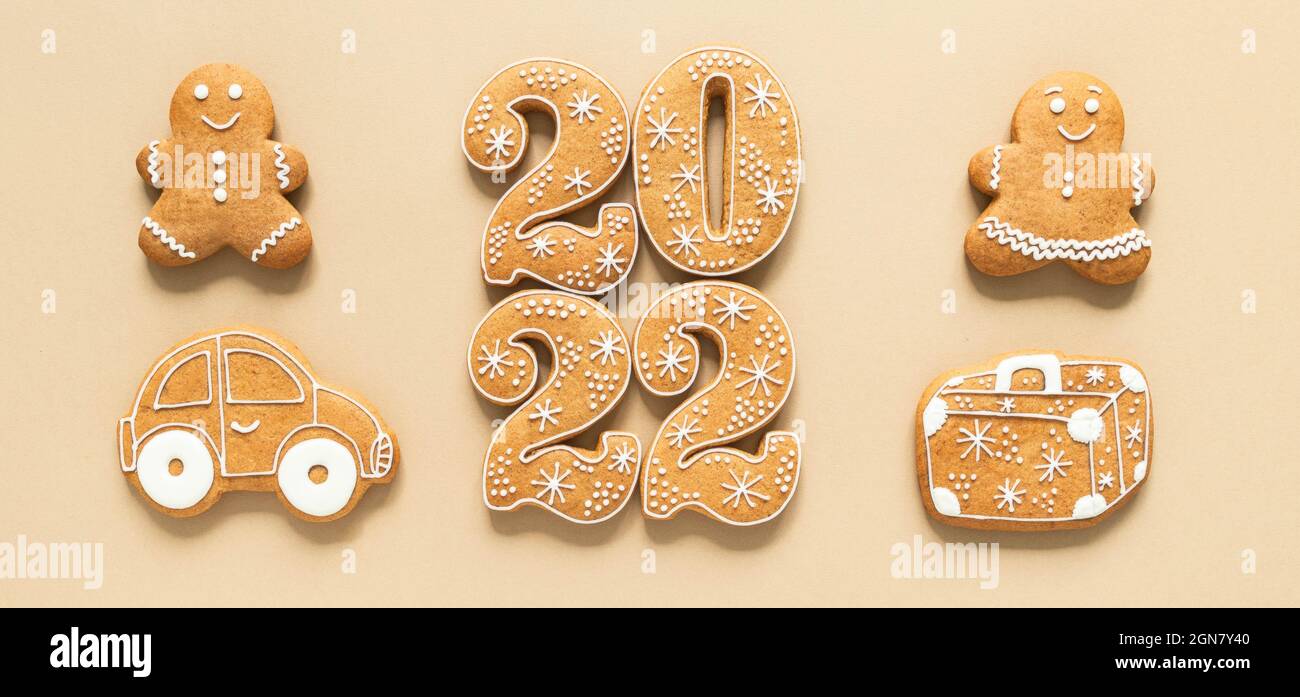 Gingerbread cookies in the form of numbers, Happy New Year 2022, gingerbread man and woman, suitcase and car on beige background. Travel concept Top v Stock Photo