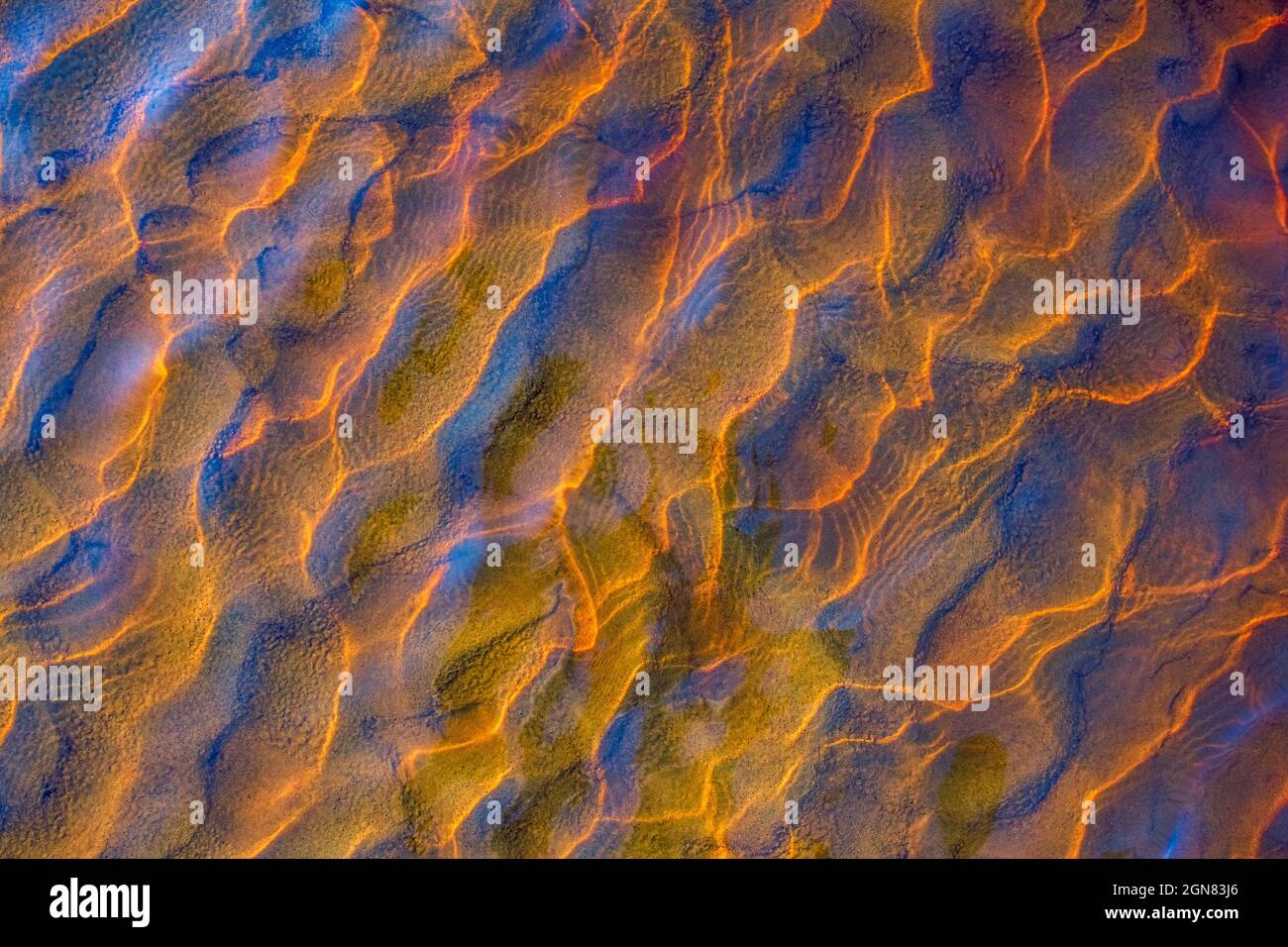 Clear golden water stream pattern with sand waves under it Stock Photo