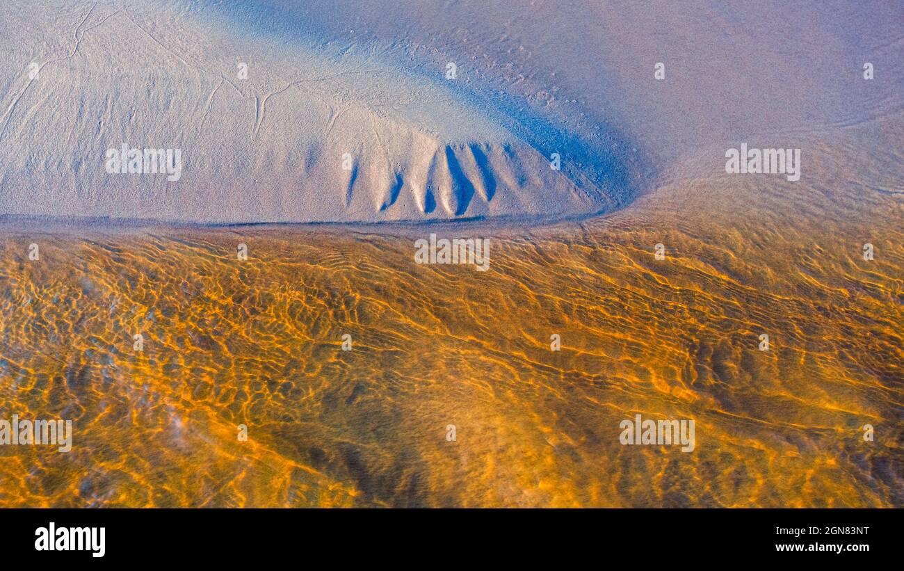 Clear golden water stream pattern with sand waves under it Stock Photo